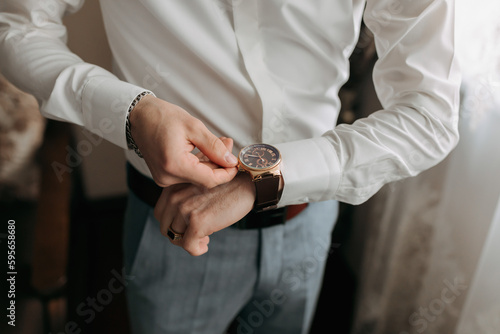 Details. A man in a white shirt puts a watch on his hand. Top view. Daylight. Fashion and style. Business. Men's style