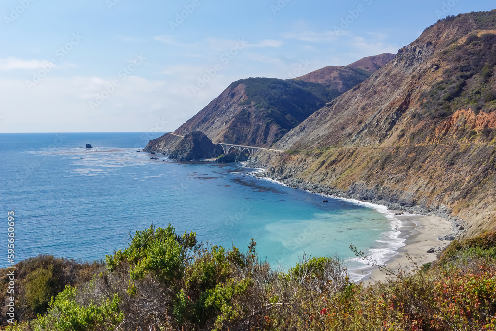 Panoramic view of Bixby Creek Bridge along rugged coastline of Big Sur with Santa Lucia Mountains along famous Highway 1, Monterey county, California, USA, America. Road trip to hidden deserted beach