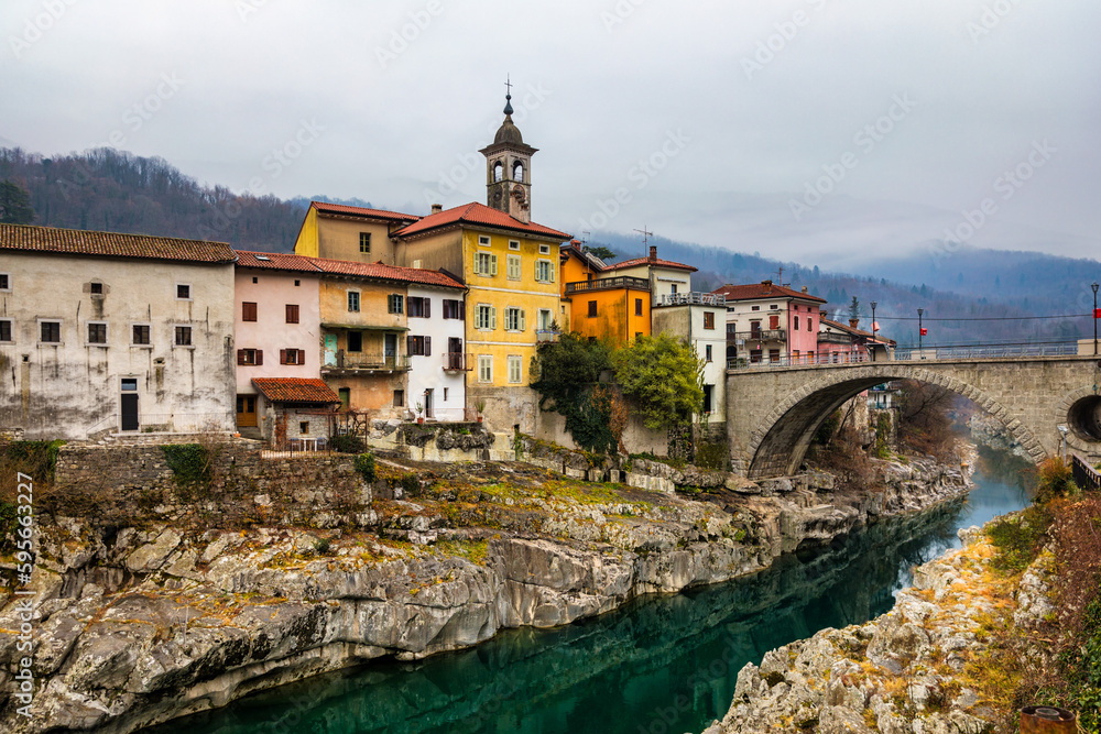 Beautiful ancient mediterranean town with stone arch bridge and emerald river. Kanal town in Slovenia. Small town of Kanal, Slovenia with the clear turquoise Soca River carving the white rocks.