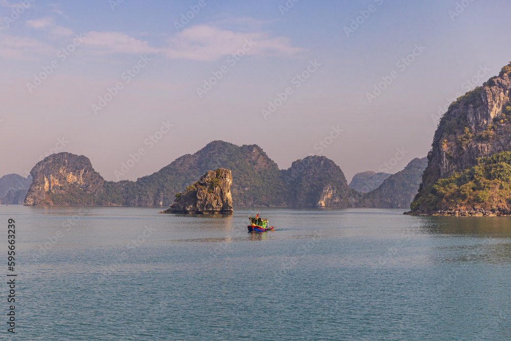 Small fisherman boat in limestone mountain scenery at Ha Long Bay, North Vietnam.