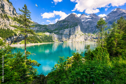 Fototapeta Naklejka Na Ścianę i Meble -  Famous Oeschinensee with Bluemlisalp mountain on a sunny summer day. Panorama of the azure lake Oeschinensee. Swiss alps, Kandersteg. Amazing tourquise Oeschinnensee with waterfalls, Switzerland.