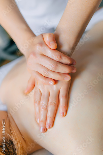 hands of professional masseur doing back massage in wellness spa  treatment concept  closeup