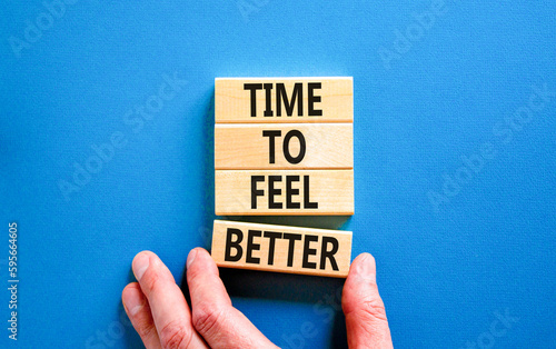 Time to feel better symbol. Concept words Time to feel better on wooden block. Beautiful blue table blue background. Businessman hand. Motivational business time to feel better concept. Copy space