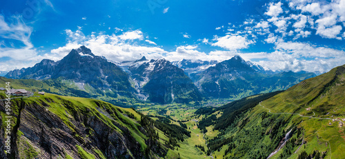Panoramic view of idyllic mountain scenery in the Alps with fresh green meadows in bloom on a beautiful sunny day in summer  Switzerland. Idyllic mountain landscape in the Alps with meadows in summer.
