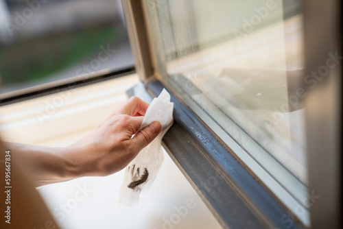 Woman cleaning window tiles with wet paper towel in sunny spring cleaning day close up of dirt and bacteria