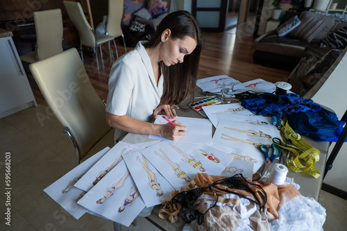 Woman draws sketches of swimwear with a pencil. 