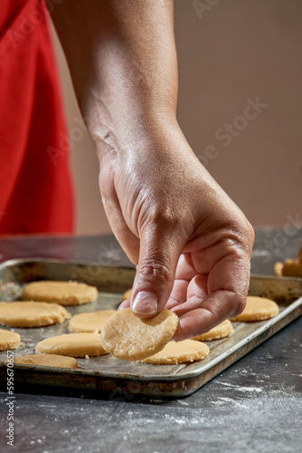 Close up of a woman's hand with a piece of raw cookies on a kitchen table soaked in flour, cookies ready to bake in oven