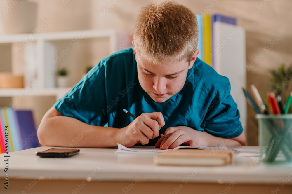 Young teenage boy holding a pen in his hand and concentrating on his homework. Young teenage boy holding a pen in his hand and concentrating on his homework.