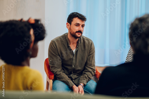 Fototapete Young man talking about his mental health on a group therapy session