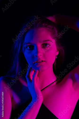 face of girl on a dark background with colored lights - art portrait