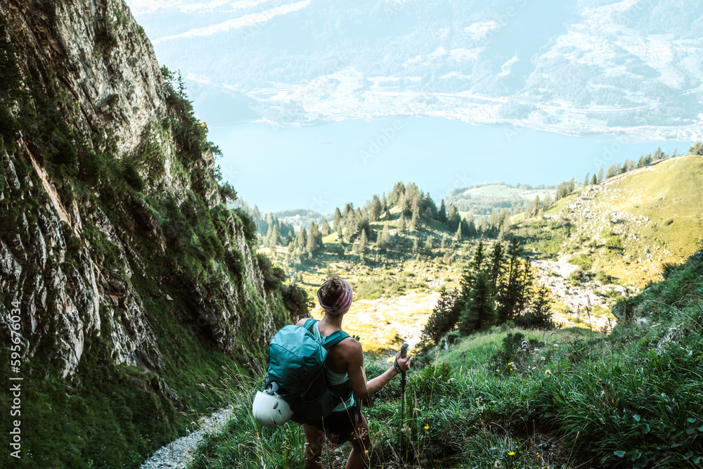 Sporty woman enjoys view from hike trail on lake Walensee in the morning.  Schnürliweg, Walensee, St. Gallen, Switzerland, Europe. Stock Photo