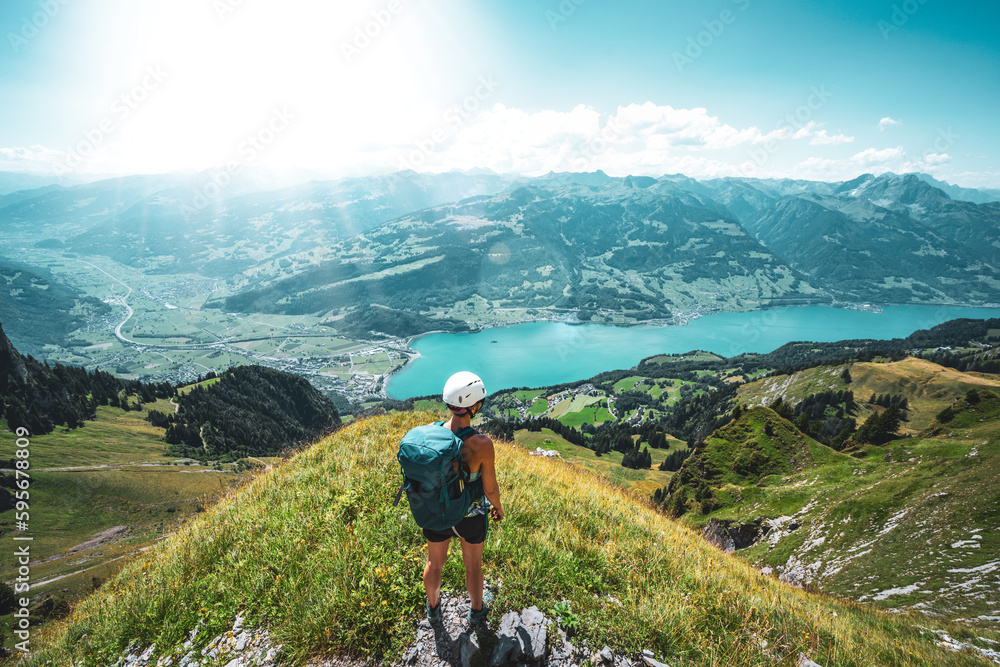 Mountaineer enjoys the panoramic view on Walensee from a beautiful view point next to the hike trail. Schnürliweg, Walensee, St. Gallen, Switzerland, Europe.