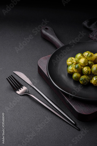 Delicious boiled Brussels sprouts on a ceramic plate on a dark concrete background