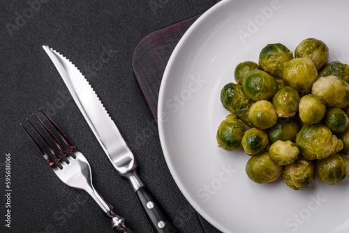 Delicious boiled Brussels sprouts on a ceramic plate on a dark concrete background