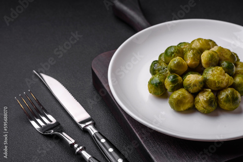 Delicious boiled Brussels sprouts on a ceramic plate on a dark concrete background