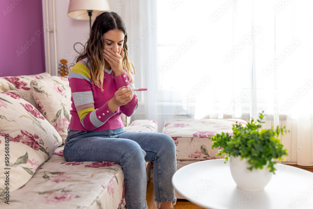 Teenager girl scared and shocked holding pregnancy test positive result looking unhappy and in depression. Unexpected pregnant girl concept Teenager girl scared and shocked holding pregnancy test positive result looking unhappy and in depression. Unexpected pregnant girl concept