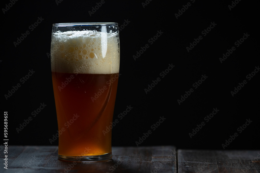 A glass of delicious craft beer served on an authentic beer glass, to be used as a background A glass of delicious craft beer served on an authentic beer glass, to be used as a background