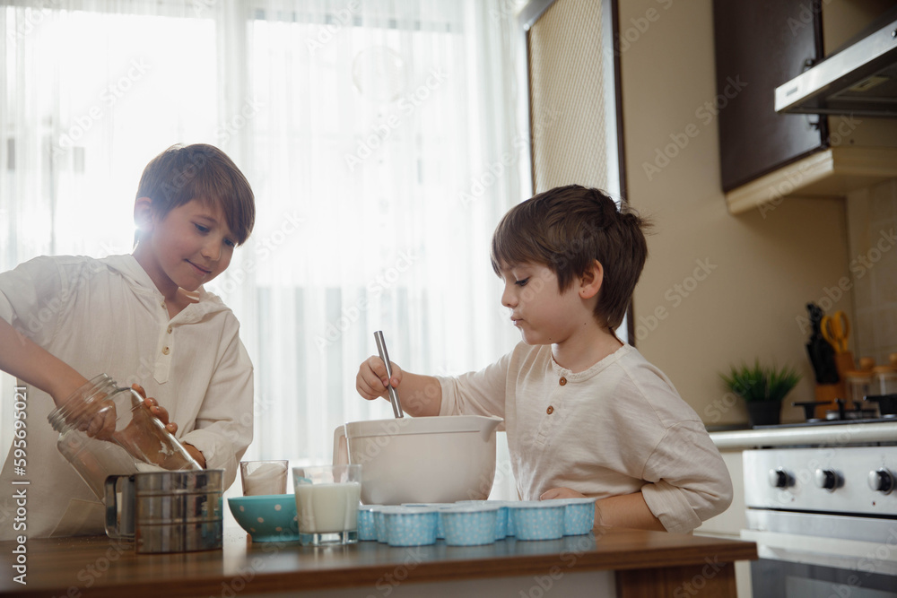 Family activities for kids. Two little boys, brothers make homemade cupcakes, preparing dough for muffins at the domestic kitchen. Family activities for kids. Two little boys, brothers make homemade cupcakes, preparing dough for muffins at the domestic kitchen.