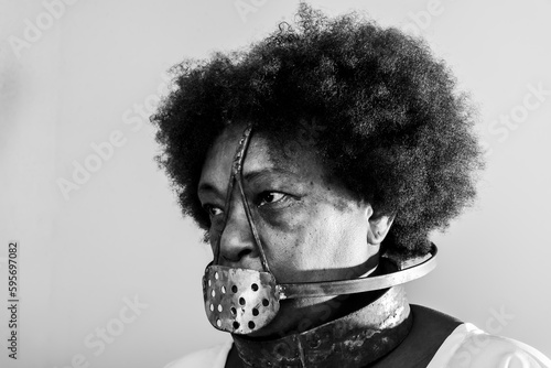 Face portrait of black woman with iron mask of slavery covering her mouth.