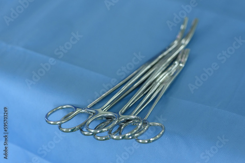 Surgical clamps and medical equipment on the surgical tray. Surgical scissors on a medical table close-up inside the operating room. Medical tools inside the operating theater on a blue table.