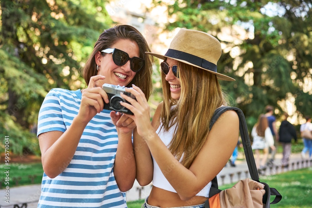 Sharing joyful moments, friends review vacation photos on camera.