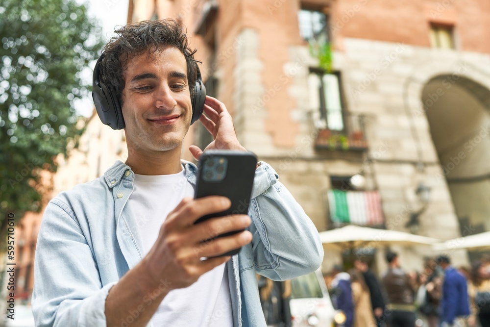 Young man enjoys the convenience of mobile music, wearing headphones and carrying his smartphone, as he finds creative inspiration on-the-go. Young man enjoys the convenience of mobile music, wearing headphones and carrying his smartphone, as he finds creative inspiration on-the-go.