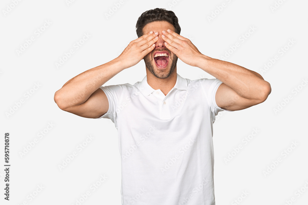 Young handsome man isolated covers eyes with hands, smiles broadly waiting for a surprise. Young handsome man isolated covers eyes with hands, smiles broadly waiting for a surprise.