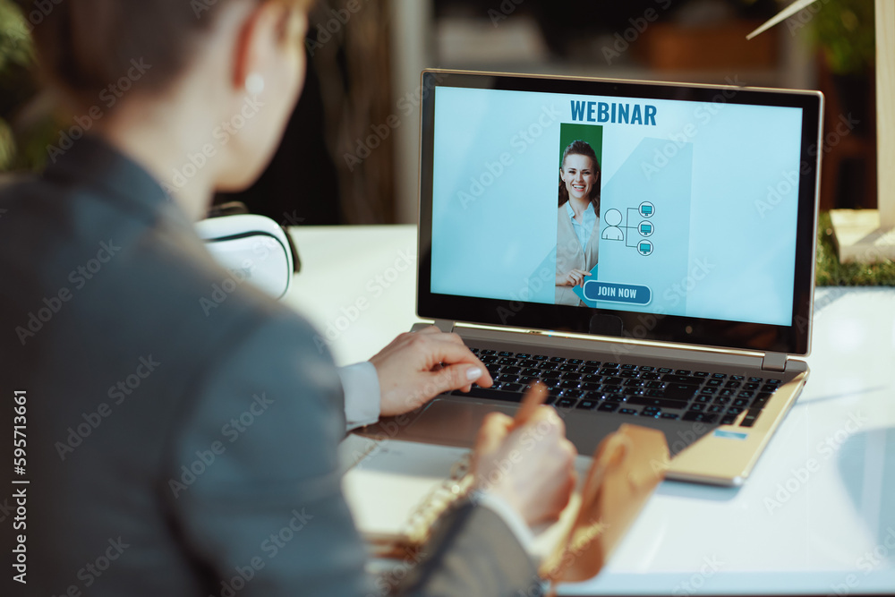 modern woman writes in notebook and watching online webinar