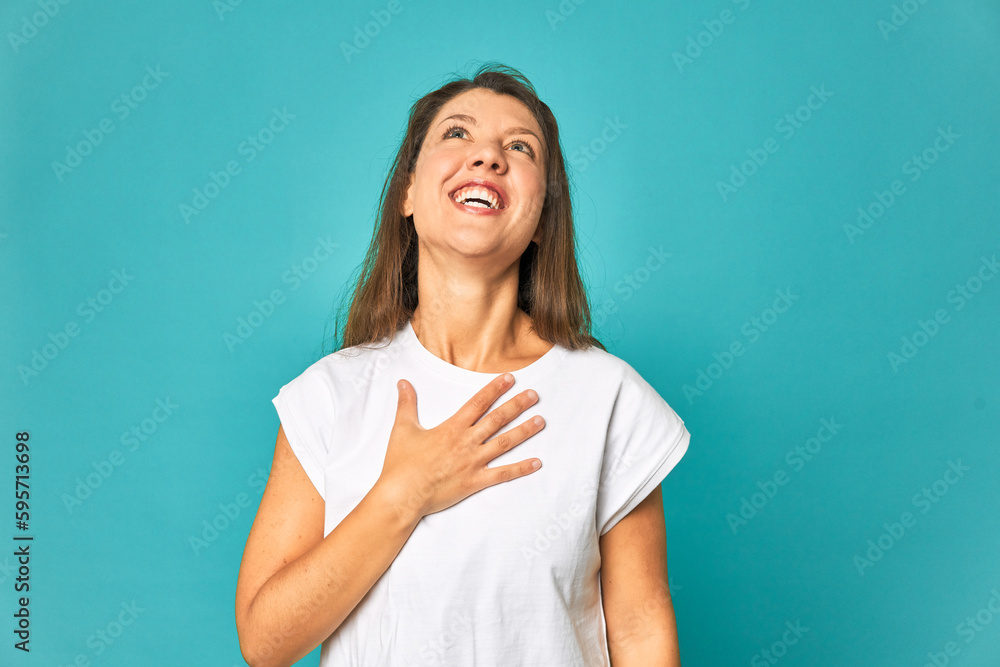 A young caucasian woman isolated laughs out loudly keeping hand on chest. A young caucasian woman isolated laughs out loudly keeping hand on chest.