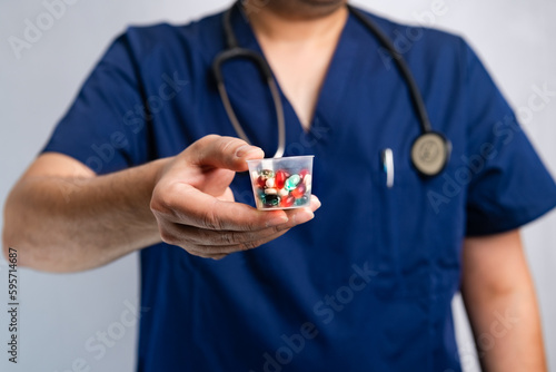 doctor holds in his hands different pills in a glass and offers them to the patient in the clinic. Close-up