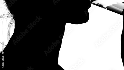 Young woman silhouette drinking water from a clear glass, close up (neck and chin)