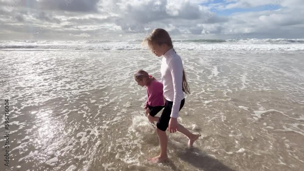 Children run along the coast of the Atlantic Ocean. Two little sisters are playing with the waves on the beach of the Atlantic Ocean. Family time or vacation concept. 4K resolution video. Children run along the coast of the Atlantic Ocean. Two little sisters are playing with the waves on the beach of the Atlantic Ocean. Family time or vacation concept. 4K resolution video.