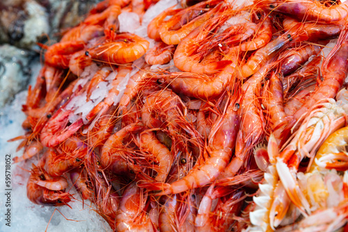 Closeup of fresh raw shrimps on crushed ice in open display of fish shop..