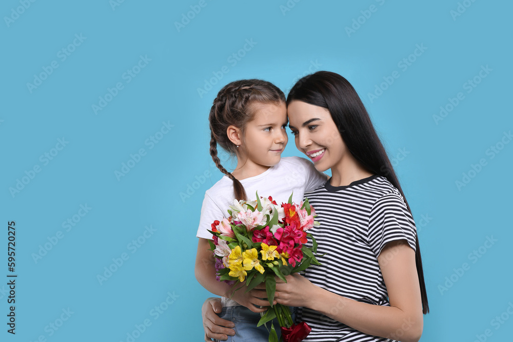 Happy woman with her daughter and bouquet of beautiful flowers on light blue background, space for text. Mother's day celebration Happy woman with her daughter and bouquet of beautiful flowers on light blue background, space for text. Mother's day celebration