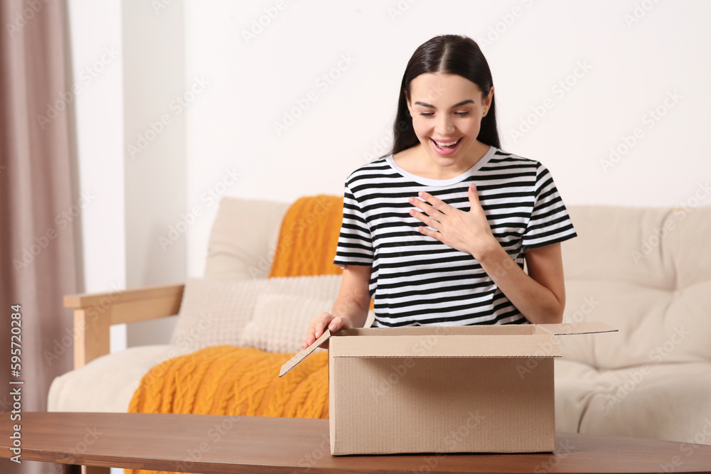 Emotional young woman opening parcel at home. Internet shopping Emotional young woman opening parcel at home. Internet shopping