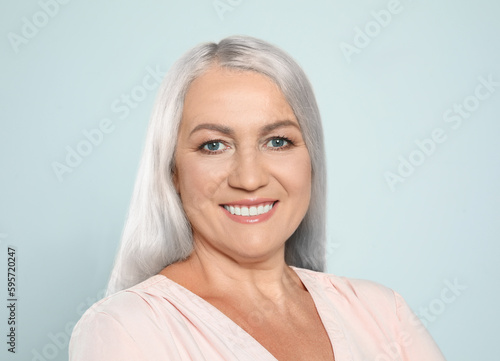 Portrait of smiling woman with ash hair color on light grey background