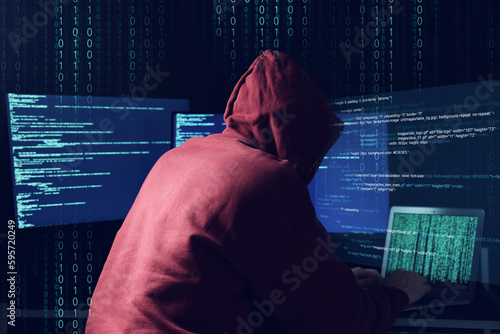 Cyber attack. Anonymous hacker working with laptop and monitors on dark blue background. Binary code around him