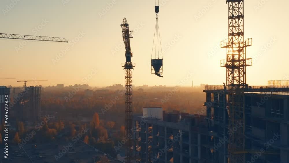 Aerial side view of a tower cranes silhouettes at the construction site of a residential building