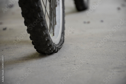 Closeup view of vintage bike which had flat wheels, parked on cement floor and waiting to repair and refill the air, soft focus. photo