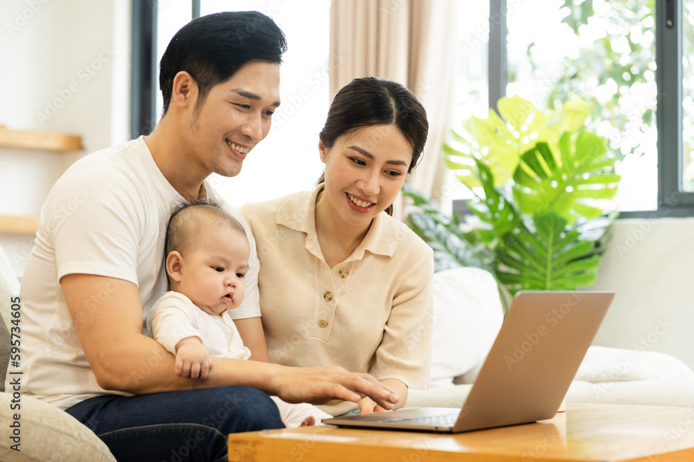 image of asian family with baby sitting on sofa using laptop image of asian family with baby sitting on sofa using laptop