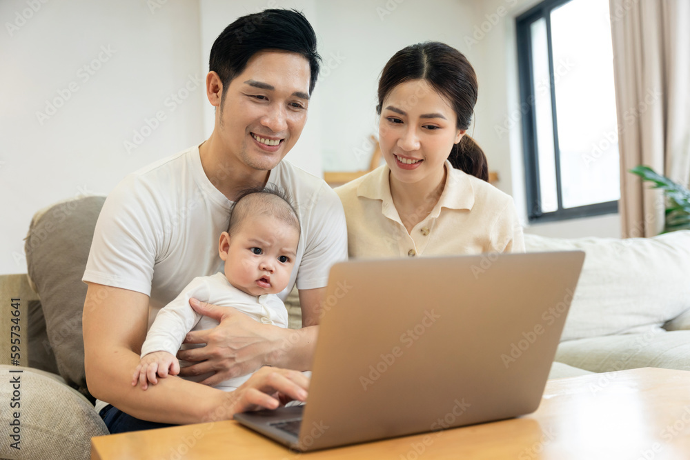 image of asian family with baby sitting on sofa using laptop image of asian family with baby sitting on sofa using laptop