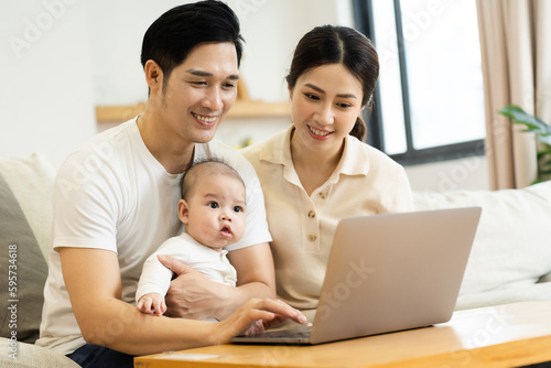 image of asian family with baby sitting on sofa using laptop