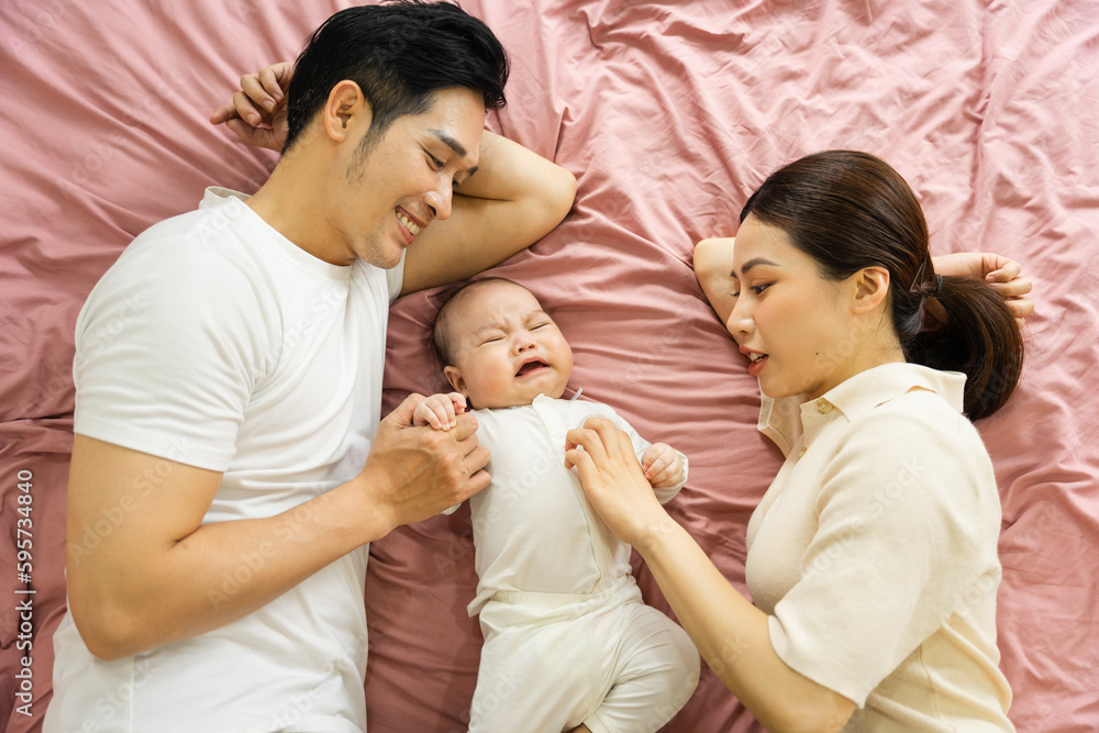 Asian family image with baby lying in bed Asian family image with baby lying in bed