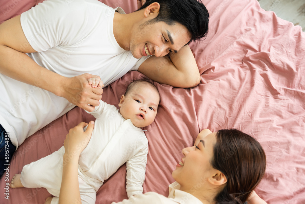 Asian family image with baby lying in bed Asian family image with baby lying in bed