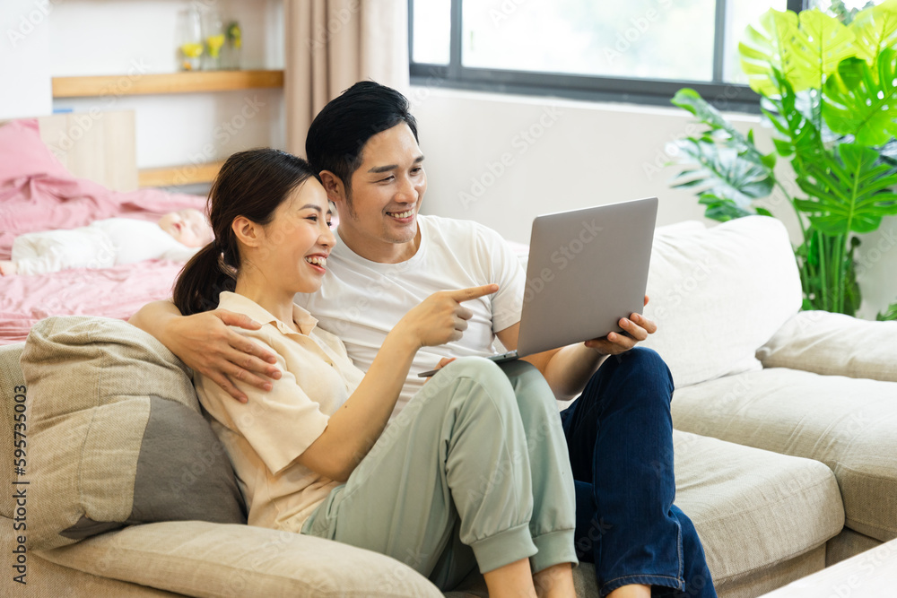 image of asian couple sitting on sofa at home image of asian couple sitting on sofa at home