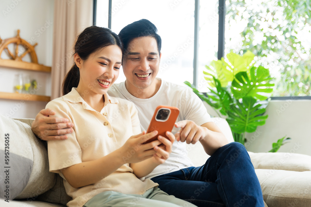 Obraz premium image of asian couple sitting on sofa at home
