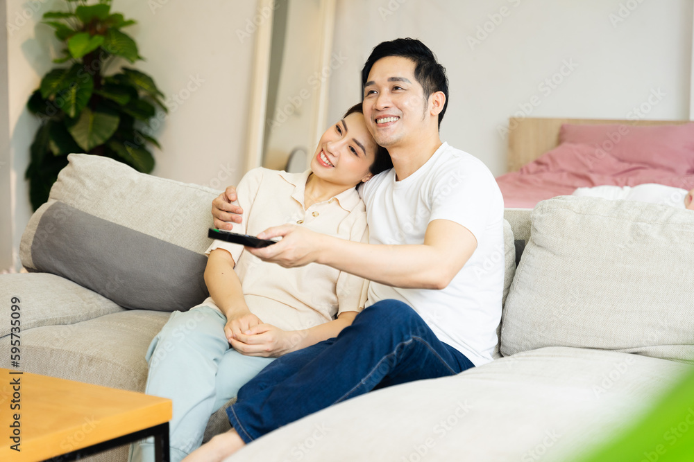 image of asian couple sitting on sofa at home image of asian couple sitting on sofa at home