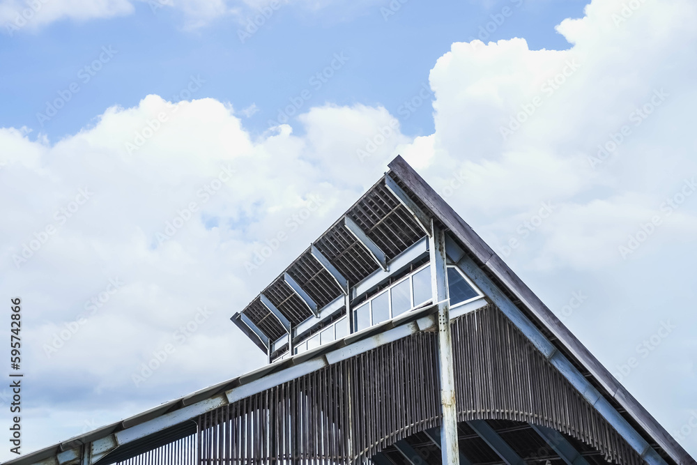 The upper part of the roof of a modern building using clay, wood, steel and glass roofing materials with sky background. Concept for modern architecture, urban home, hotel, cafe, restaurant design.