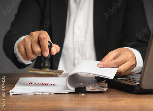 Businessman stamped rejected on a document while sitting in the office