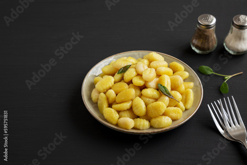 Homemade Easy Potato Gnocchi on a Plate on a black background, side view. Space for text.